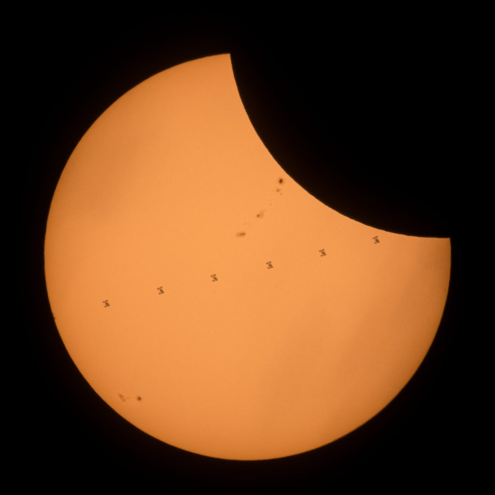 Composite of the International Space Station silhouetted against a partially eclipsed Sun